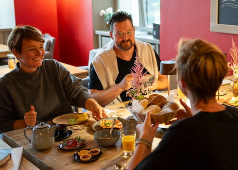 Menschen lachen und frühstücken auf Schloss Kaarz im Roten Salon.