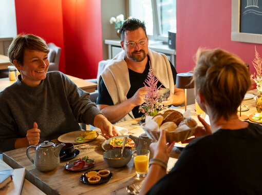 Menschen lachen und frühstücken auf Schloss Kaarz im Roten Salon.