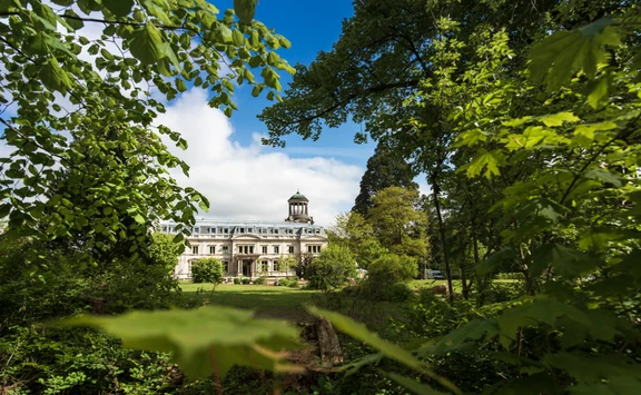 Umgeben vom Grün der Natur ist Schloss Kaarz eingerahmt. Eine Außenansicht an einem sonnigen Tag.