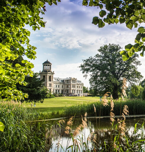 Hotel Schloss Kaarz Schlossansicht mit Blick über den Teich und durch die grüne Natur