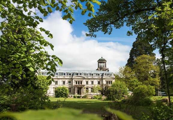 Umgeben vom Grün der Natur ist Schloss Kaarz eingerahmt. Eine Außenansicht an einem sonnigen Tag.