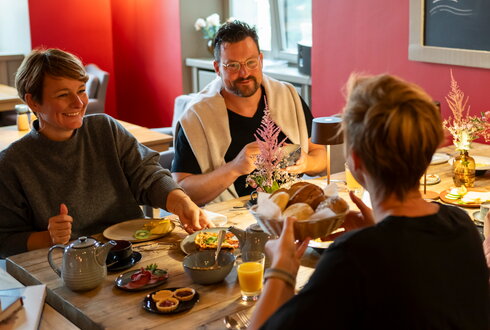 Menschen lachen und frühstücken auf Schloss Kaarz im Roten Salon.